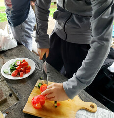 キャンプ料理でナイフで野菜を切る少年の手元