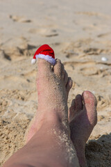 santa claus hat on a finger in the sand