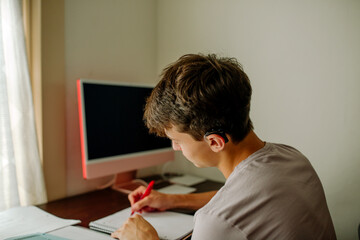 Teen with cochlear implant at home desk