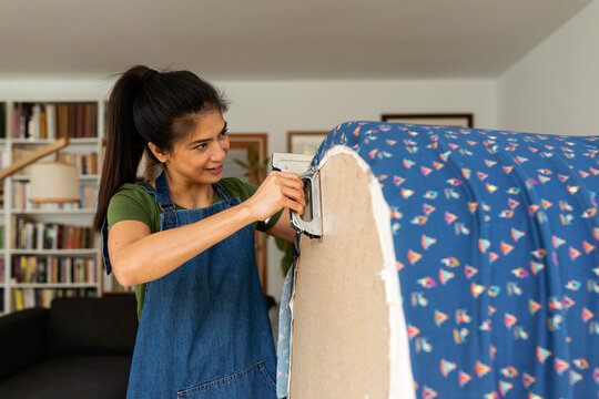 Asian woman upholstering chair with stapler
