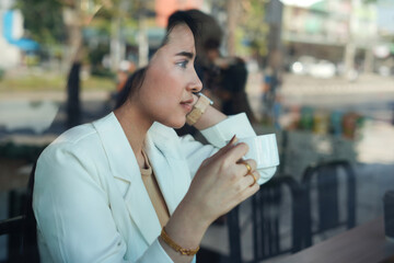 attractive business woman thinking and having a coffee, view through glass window in the urban