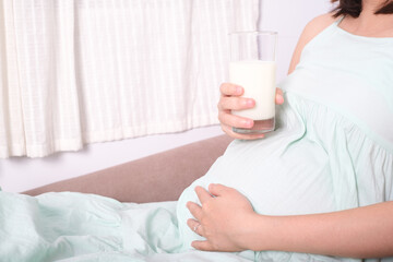 Fototapeta na wymiar Young pregnant woman drinking milk sitting on sofa in the living room. healthy food eating for life.