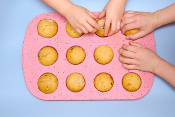 Homemade muffins. Kid's hands take muffins from the baking dish.