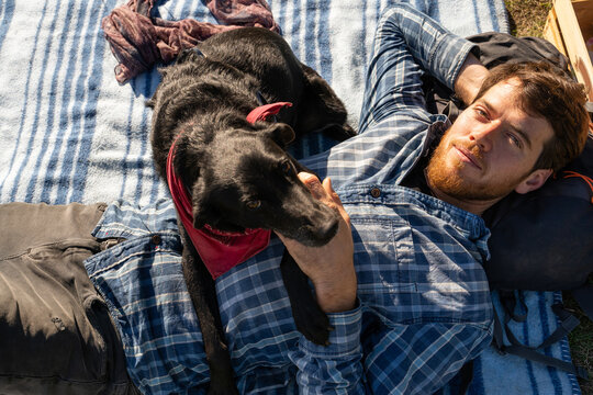 Portrait Man and dog laying on grass in park 