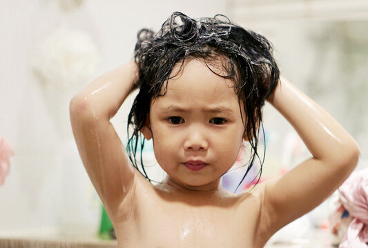 Cute Asian little girl washing her hair in bathroom


