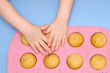 Homemade muffins. Kid's hands take muffins from the baking dish.