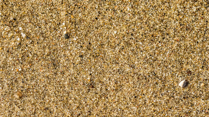 A background of sand, small pebbles and flowing waves on the sea beach. Summer vacation concept
