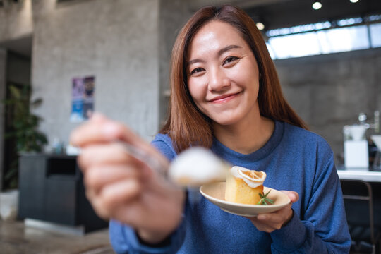 Portrait image of a young asian woman holding, showing and eating a piece of lemon pound cake