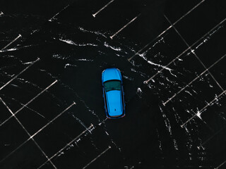  blue sedan car crossing a parking, drone overhead view