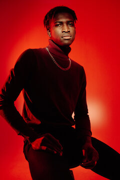 African American guy sitting on red background