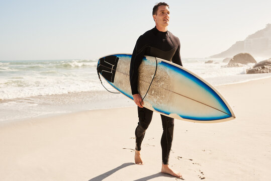 Male surfer with surfboard walking along beach