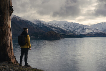 Fototapeta premium Man standing by a tree in Lake Hawea during winter.