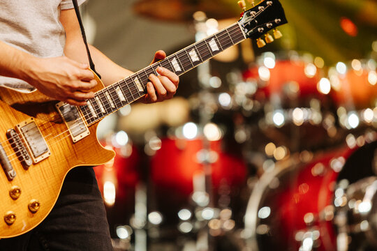 Crop musician playing guitar in live concert