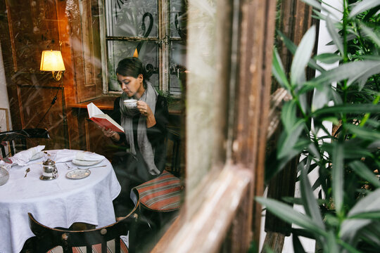 Woman Reading Book in Cozy Cafe