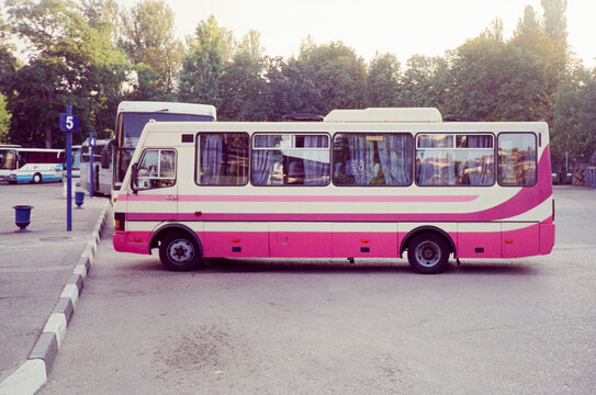 Vintage bus with pink stripes parked in a bus station