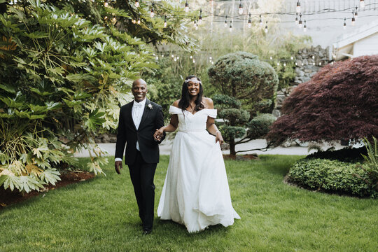 Smiling Bride and Groom Walk in Garden