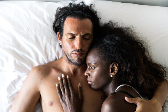 Loving diverse couple cuddling in bed