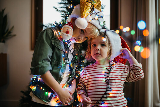 Siblings posing for a picture in front of the Christmas tree