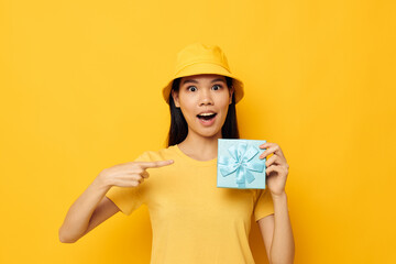 woman with Asian appearance in a yellow T-shirt and a hat with a gift studio model unaltered