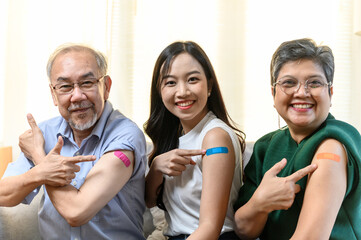 Group of diverse age Asian people family senior showing bandage plaster on arm after received covid...
