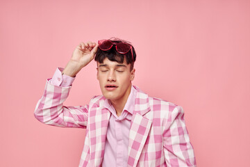 A young man pink glasses checkered jacket fashion posing pink background unaltered