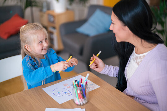 Woman helping girl to draw picture