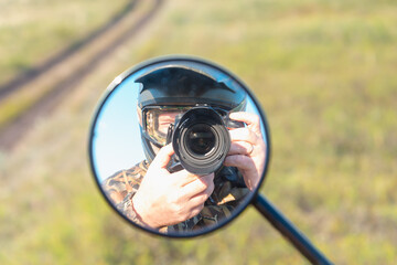 Motorcyclist with a camera in a helmet. Reflection in the mirror of a motorcycle. Motorcycle travel.