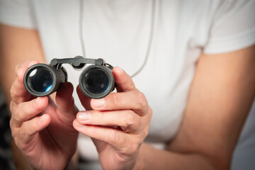 An elderly woman (old lady) holds binoculars in her hand. An elderly lady and her hands.