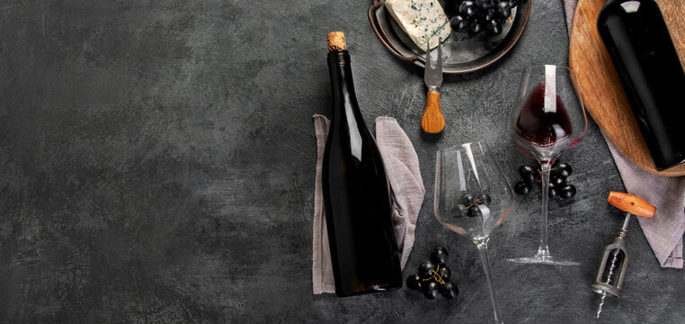 Red wine assortment with appetizers on gray background.