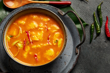 Yellow curry with chicken in bowl on dark background.