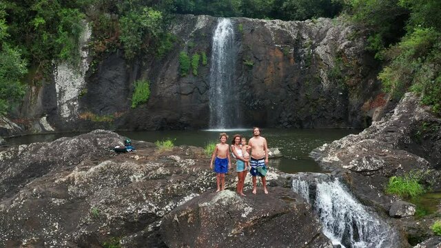 Family near a waterfall in the tropics. Vacation in the rainforest, beautiful man, woman and children journey through the countries of asia