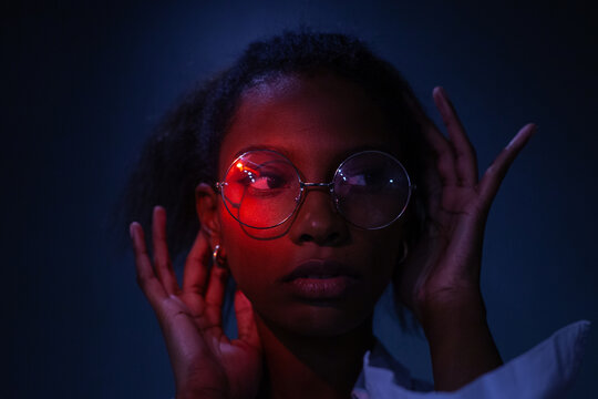 female studio portrait in neon light, wearing glasses