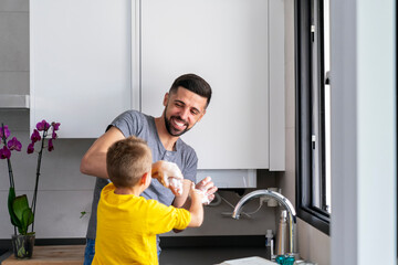 man having fun playing with his son in the kitchen