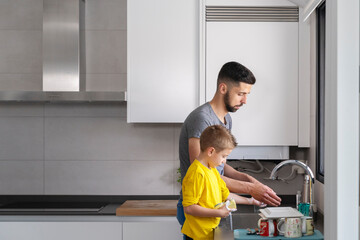 boy emulating his father cleaning the dishes