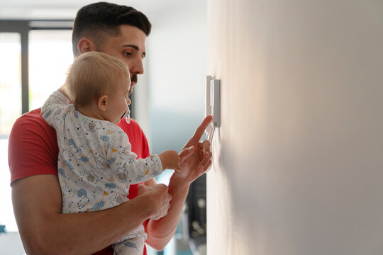 father with his baby touching a device on the wall
