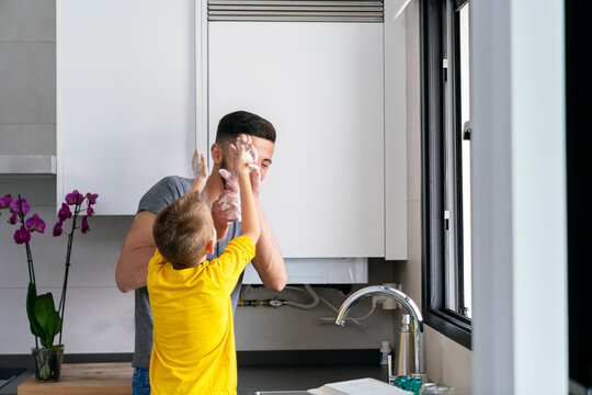 father and son playing with their hands full of foam