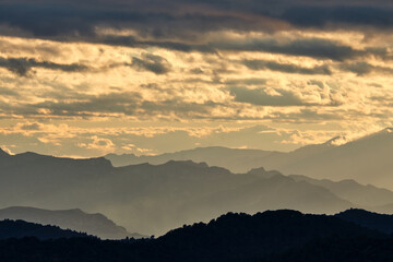silhouette of mountains at sunset with a cloudy sky of colors.