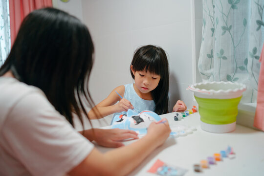 Mother painting mask with little girl