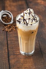 Iced coffee frappe with whipped cream in glass cup on wooden table