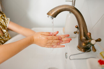 Kid's hands under tap water