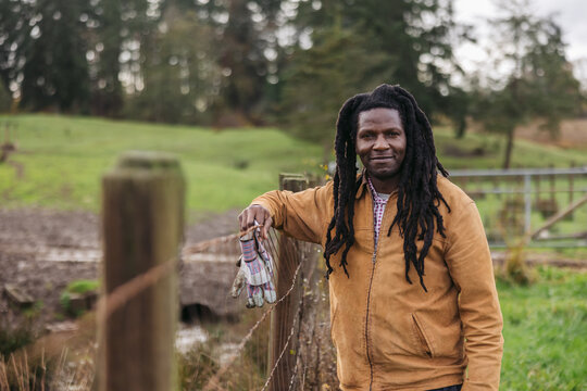 Farmer portrait standing near fence in field