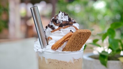 Yummy sweet coffee drink with cream and cookies topping with chocolate and caramel, using eco metal reusable straw