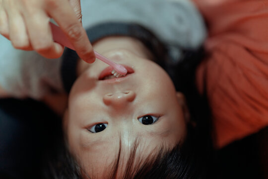 mother help little girl brush teeth