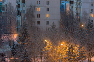 Winter snowy Troitsk town in the evening. Cozy light in windows in buildings and on the street