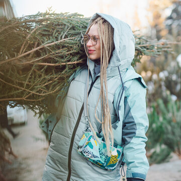 Woman with blond braids carrying a fir tree
