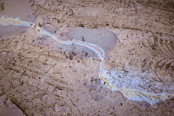 Fototapeta na wymiar Gasoline or oil on the background of a puddle on a country road