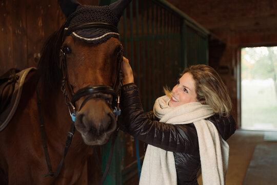 Woman stroking and reassuring her horse