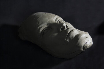 Distorted face in clay. Head sculpture in process of creation. Light and shadow. 