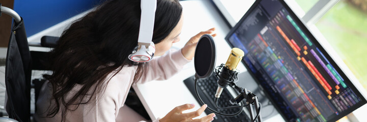 Woman in wheelchair in headphones with microphone is conducting online live broadcast