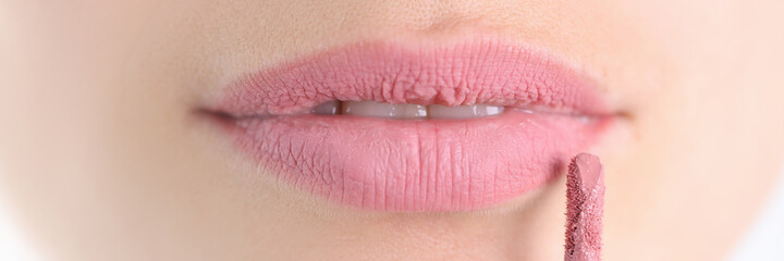 Painted female lips with lipstick brush closeup